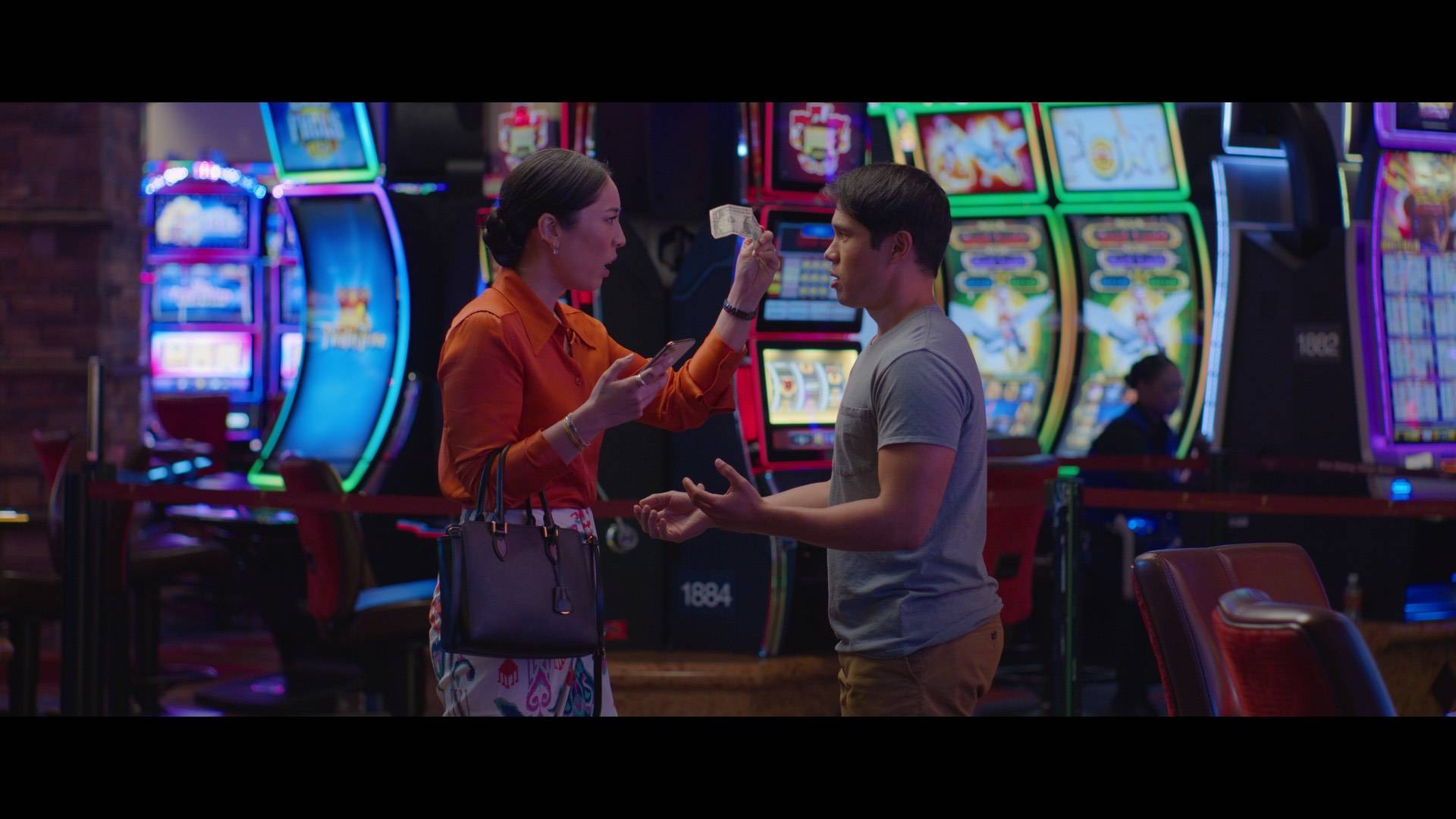 Woman lifts up a dollar bill up to man in a casino