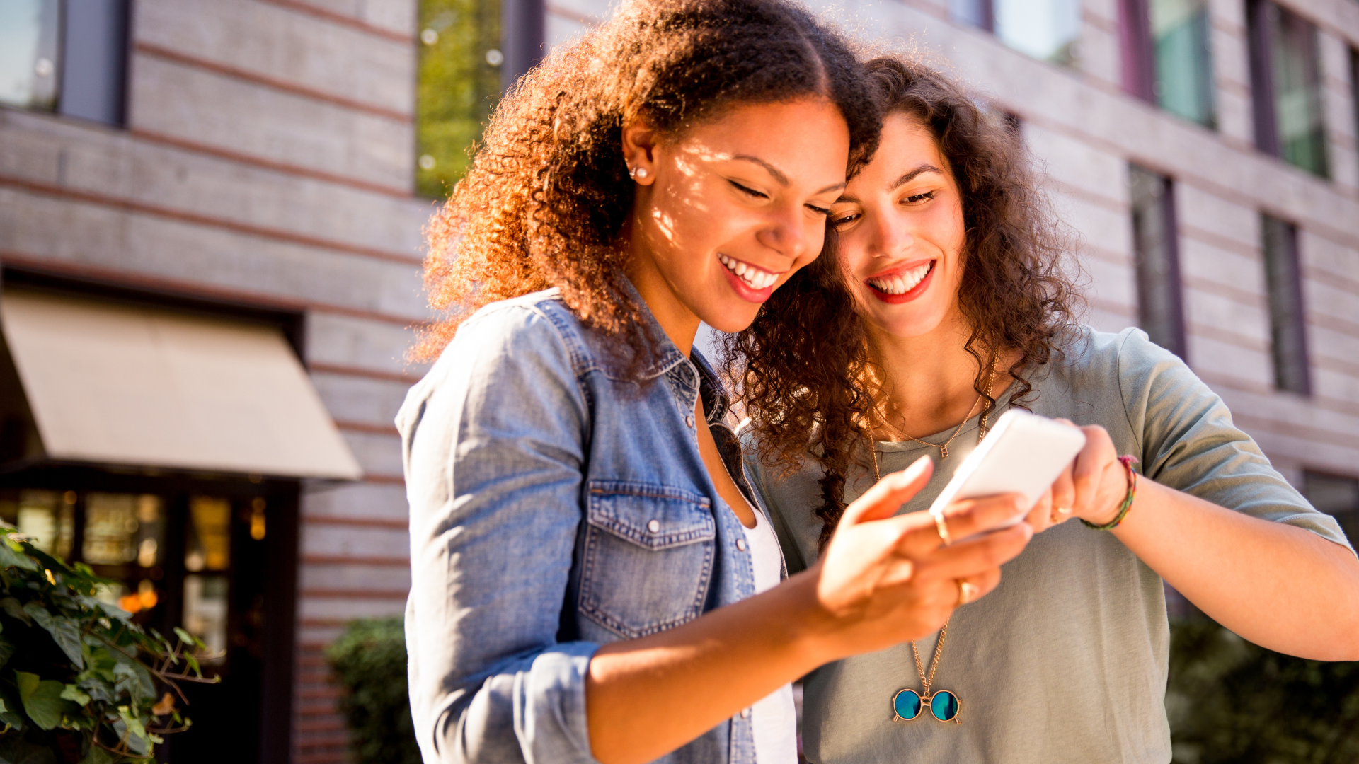 two women next to each other looking at a smartphone