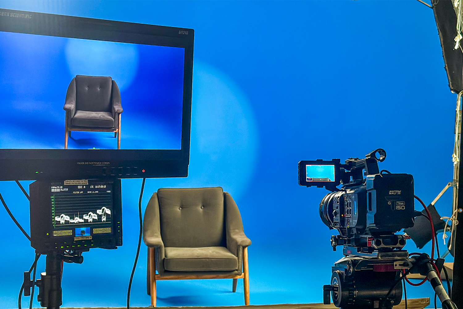 Professional video production setup featuring a camera and monitor focused on a single chair in front of a seamless blue backdrop, inside The Film Hub stage 2