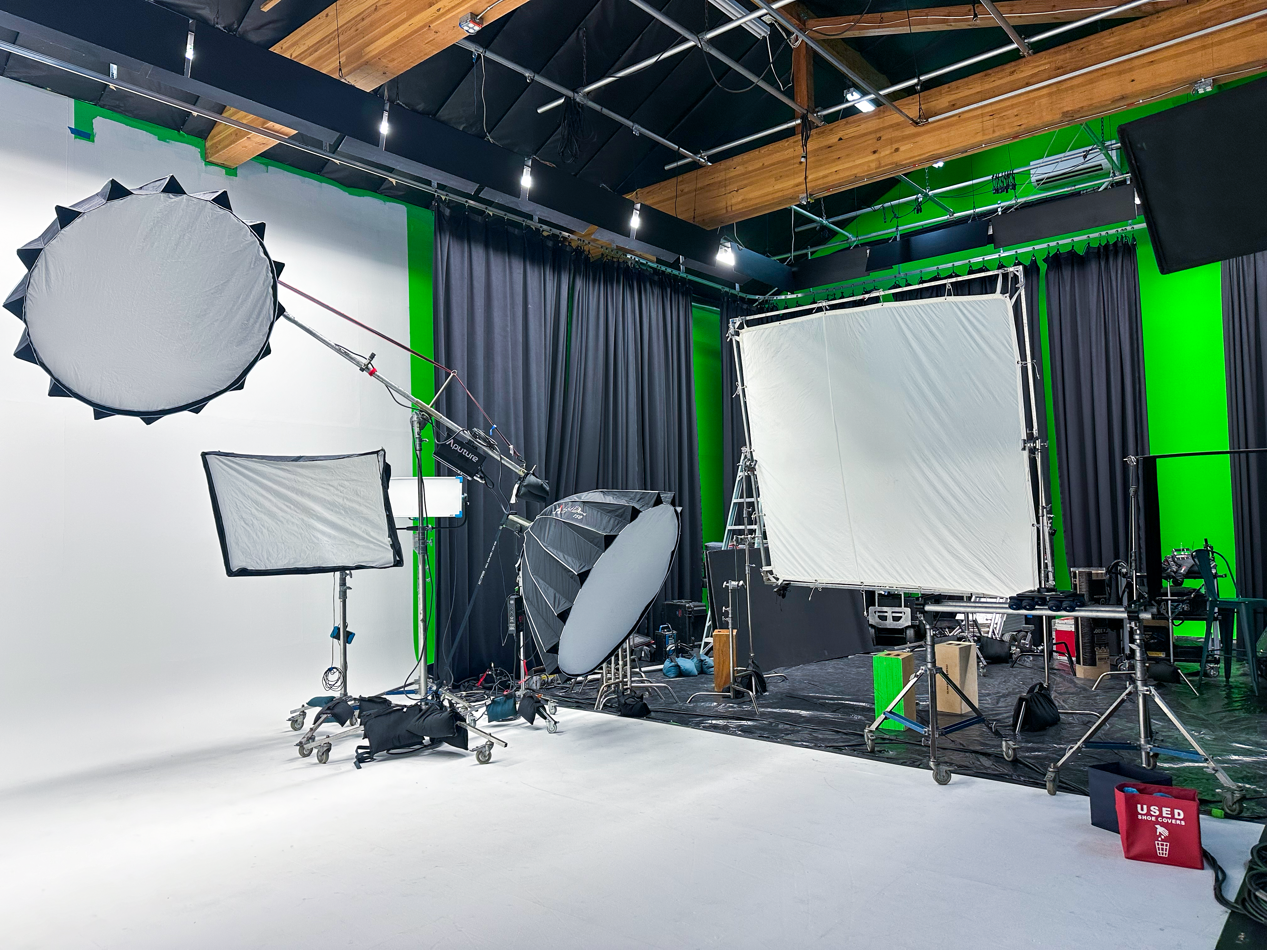 Professional soundstage at The Film Hub equipped with lighting modifiers, green screen walls, and a white cyc floor — ideal for high-end video production, commercial shoots, or VFX work.