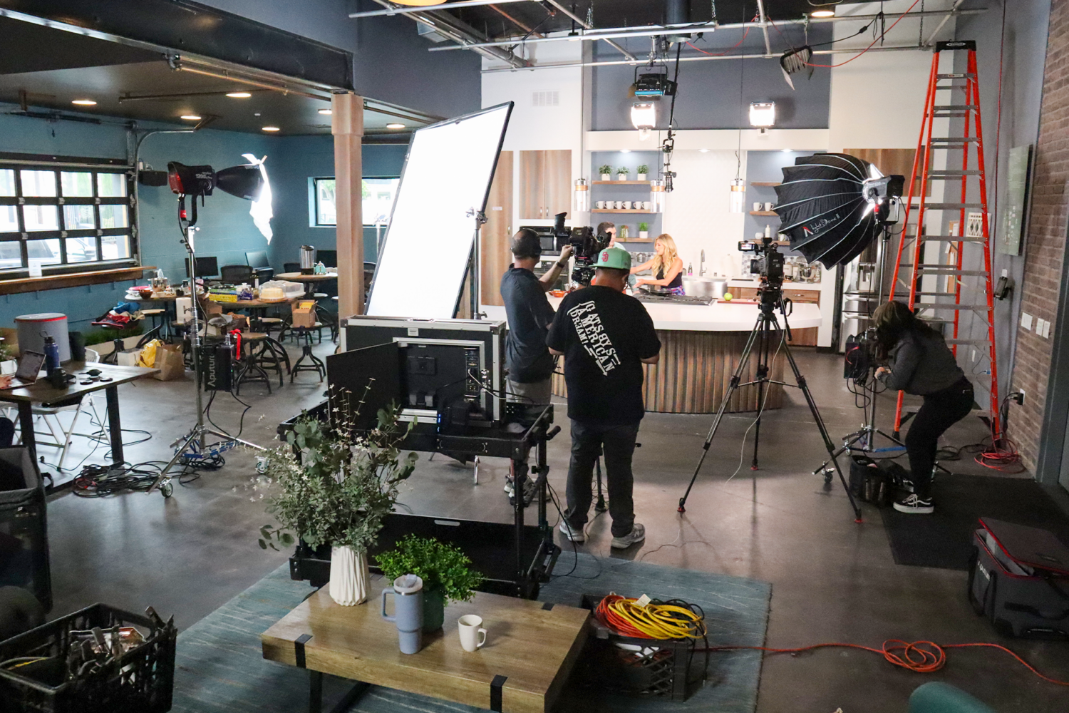 Professional video production crew filming commercial content in The Film Hub’s fully equipped kitchen studio, featuring a functional set kitchen, production lighting, cameras, and a spacious content creation environment.