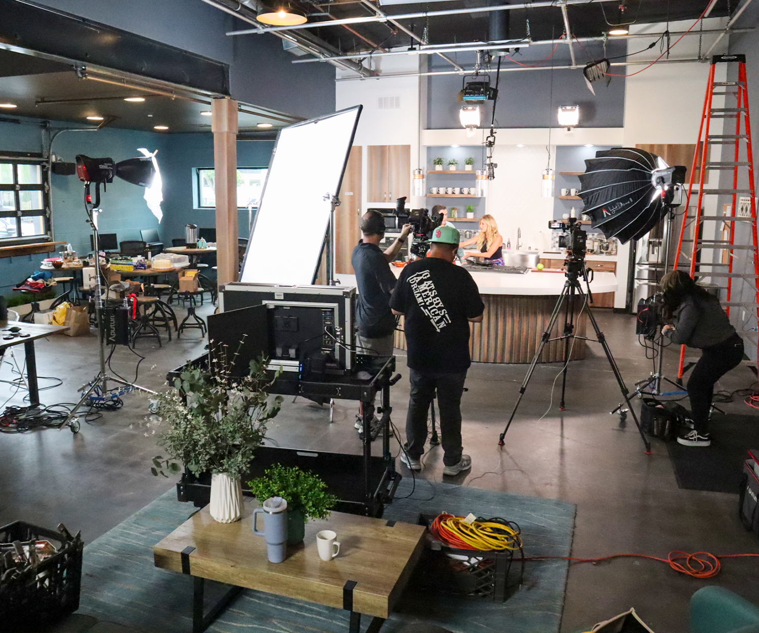Professional video production crew filming commercial content in The Film Hub’s fully equipped kitchen studio, featuring a functional set kitchen, production lighting, cameras, and a spacious content creation environment.